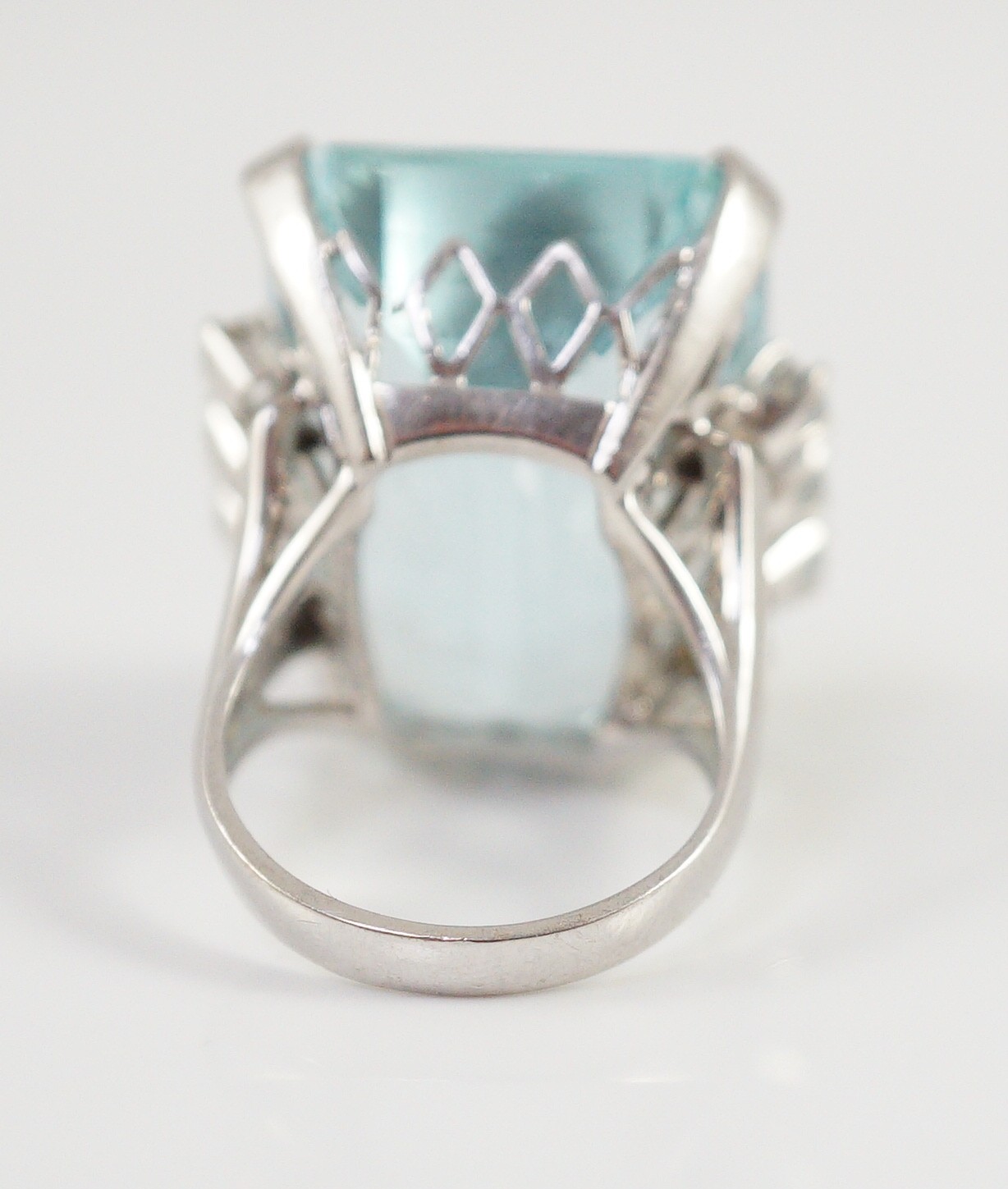 A large modern 14k white gold and emerald cut aquamarine set dress ring, flanked by six round cut diamonds